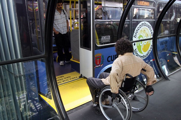 Foto de um cadeirante embarcando em um ônibus por um elevador acessível